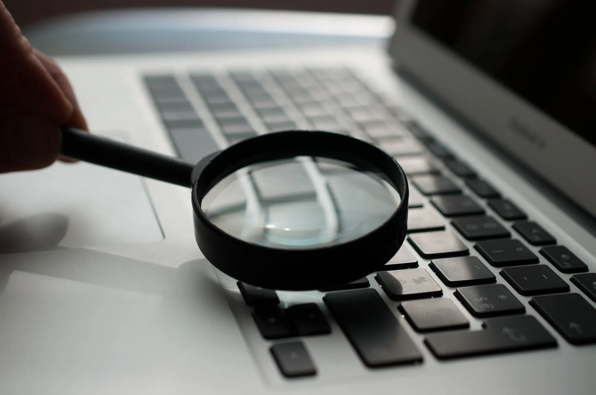 magnifying glass sitting on top of a laptop