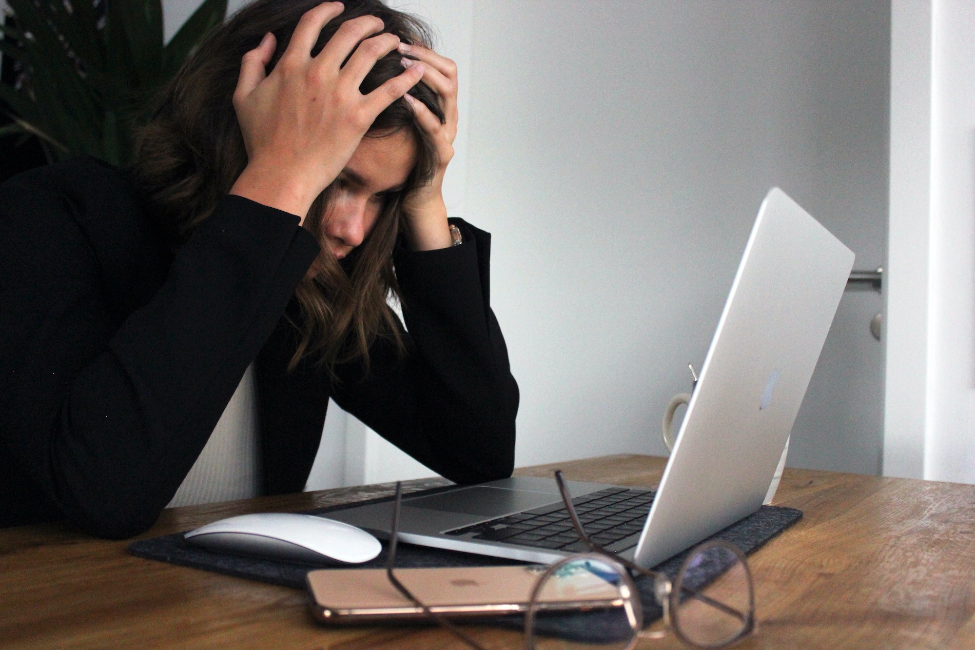 woman holding head in frustration while staring at laptop